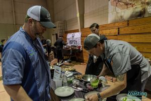 event host watches as chef plates the last of his dishes for food competition
